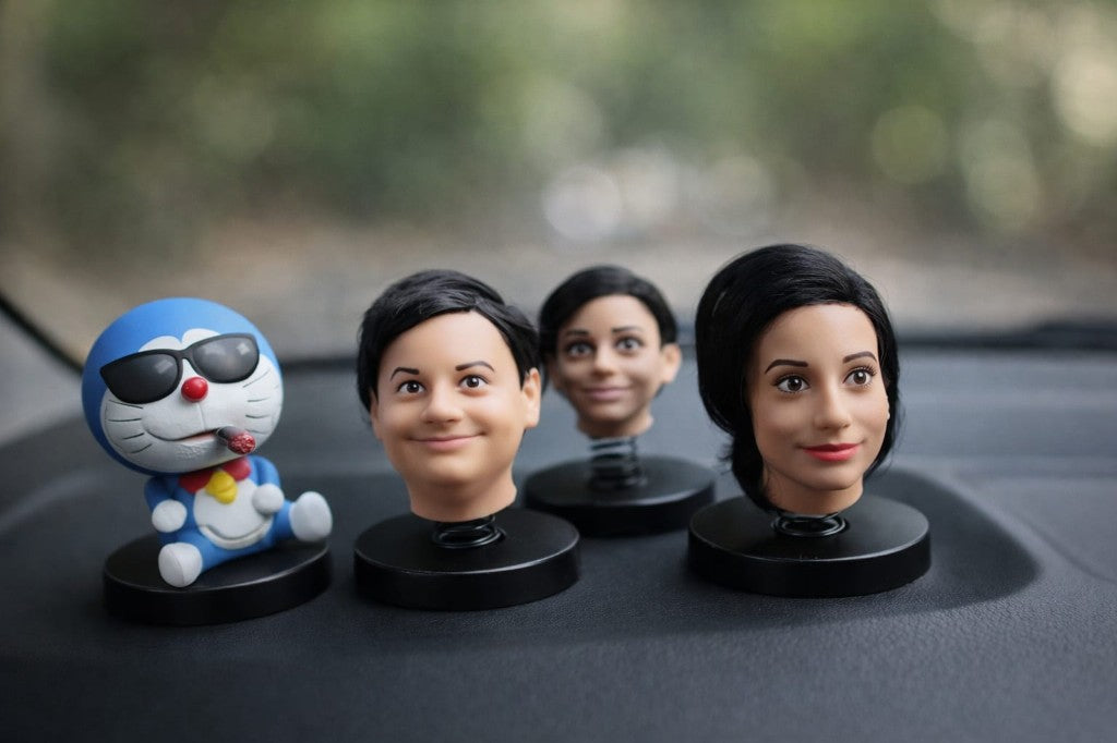 Custom bobblehead miniatures displayed on a car dashboard